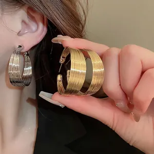 Textured gold and silver hoop earrings with a modern geometric C-shape design