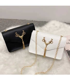 Detail of elegant deer head metal buckle and chain strap on black and white square bags
