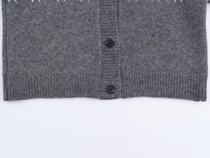 Close-up of grey knit cardigan featuring ribbed hem detail and two black buttons