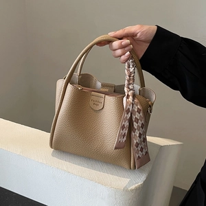 Chic khaki bucket bag with lychee texture and silk scarf accessory on white steps
