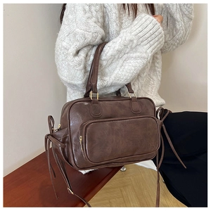 Detail of vintage brown leather handbag with long fringe tassel on wooden background