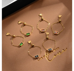 Detailed view of adjustable gold chain rings with colorful gemstones and heart charms