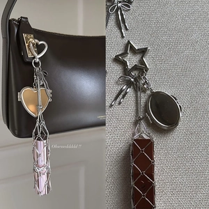 Detailed view of a stainless steel lipstick net pendant with heart locket charm on bag