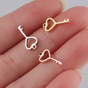 Detailed macro view of heart key pendants in gold, silver, and rose gold on a palm