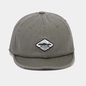 Detail of olive green cotton baseball cap with embroidered mountain travel patch