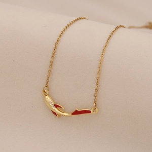 Elegant golden koi fish pendant necklace with red enamel accents on a beige fabric background
