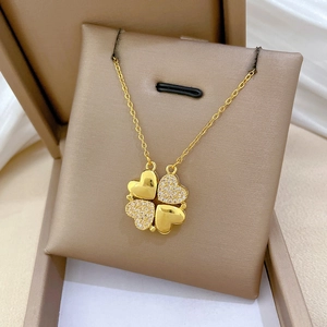 Detail of clover necklace with crystal inlay and polished gold finish in a beige box