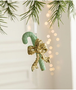 Detail of green glitter candy cane ornament with gold bow on Christmas tree branch