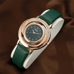 Detail of rose gold rhinestone watch with green leather strap on luxury silk