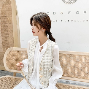 Detail of tweed vest with gold buttons and white ribbon blouse in an elegant outfit