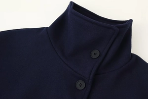 Detailed view of the high neck collar and black buttons on a navy blue wool coat