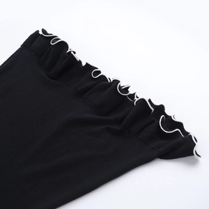 Detalle de vestido de punto negro con bordes ondulados en contraste blanco y textura