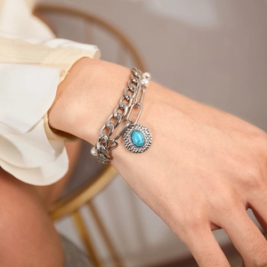 Detail of silver double-layered bracelet with pearl and turquoise stone pendant on wrist