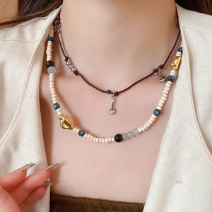 Detail of layered bohemian necklace with beads, silver charms and golden accents on a model