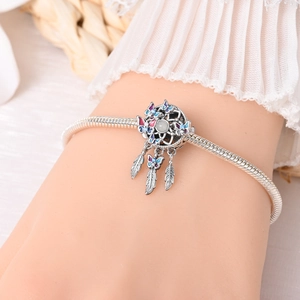 Detailed view of silver charm bracelet with dreamcatcher moon pendant and butterfly charms