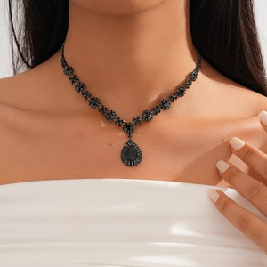 Close-up of a vintage black teardrop gemstone necklace with intricate floral crystal details