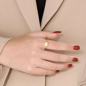 Close-up of minimalist gold heart ring on model hand with elegant beige blazer