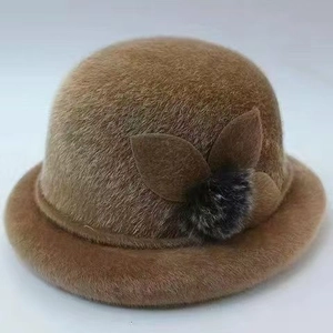 Detail of warm brown plush winter bucket hat with leaf ornaments and a grey fur ball