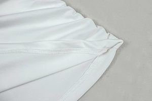 Detail of white asymmetric dress showing high-quality stitching and elastic fabric texture