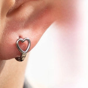 Detail shot of heart-shaped silver earrings featuring a minimalist hollow design