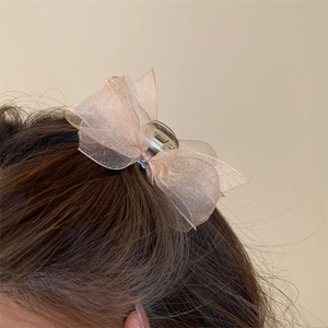 Detail showing elegant champagne mesh bow hair claw clip worn on dark hair