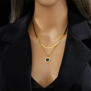 Double-layer gold snake chain necklace with a black round pendant on a model