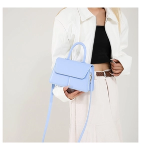 Light blue PU leather square bag with top handle shown on model wearing white jacket