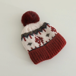 Dettaglio del berretto in maglia Fair Isle con pompon bordeaux e motivi geometrici