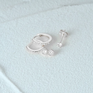 Macro shot of silver huggie hoops and stud earring set with cubic zirconia on stone