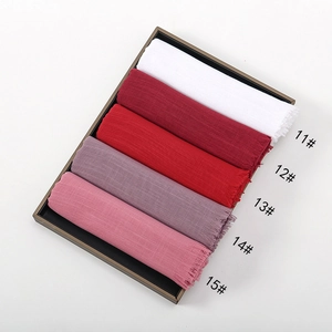 Close-up of rolled slub cotton scarves with fringe trim in five vibrant colors on tray
