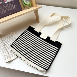 Detail of striped knit tote bag featuring cream fabric handles and magnetic button closure