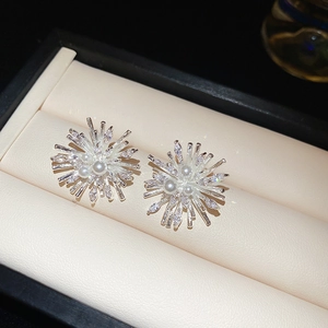 Macro shot of silver fireworks stud earrings with white pearl and sparkling zircon in box