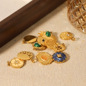 Golden celestial moon and star pendants with green and blue stones on beige fabric