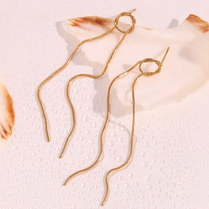 Macro detail of 18K gold plated snake chain tassels resting on a white seashell background