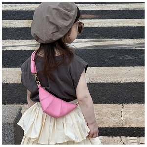 Pink horn-shaped kids crossbody bag shown on model back view over zebra crossing