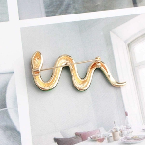 Detailed back view of gold-tone snake brooch showing metal pin and green enamel edges