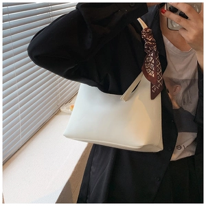 Close-up of white minimalist underarm bag featuring a stylish decorative printed scarf