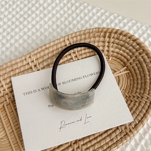 Detail of grey marble acetate hair tie with golden France Handmade logo on soft cloth