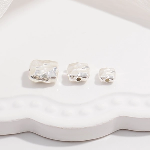Close-up of three square hammered S925 silver beads with irregular vintage texture