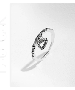 Macro shot of S925 silver ring featuring a dangling heart charm with black pavé stones