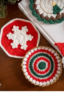 Detail of handcrafted crochet Christmas coasters with snowflake patterns and gold trim