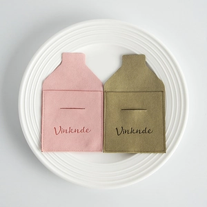 Detalle de bolsas de microfibra para joyas en rosa y verde en plato cerámico