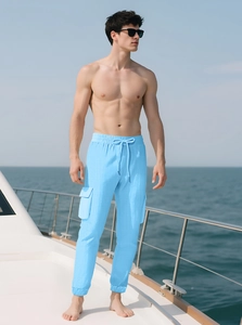 Detailed shot of sky blue cargo pants featuring waffle texture and drawstring on a yacht