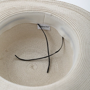 Detail of woven straw hat interior with sweatband, brand label, and elastic chin strap