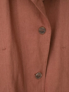 Detail of rust red faux suede jacket showing linen texture and tortoiseshell buttons