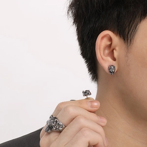 Close-up of men's vintage tiger head ring and stud earrings in embossed silver metal