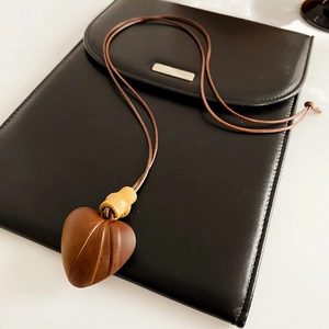Detailed view of wood heart pendant with bamboo design on a sleek black leather surface