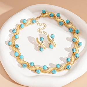 Gold turquoise and diamond geometric necklace and earring set on a white decorative plate