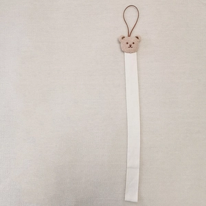 Detail of plush bear head on beige fabric hanging strap for children hair accessories