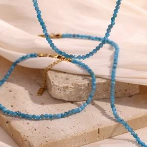 Close-up of blue natural stone bead necklaces with 18K gold plated clasps on stone